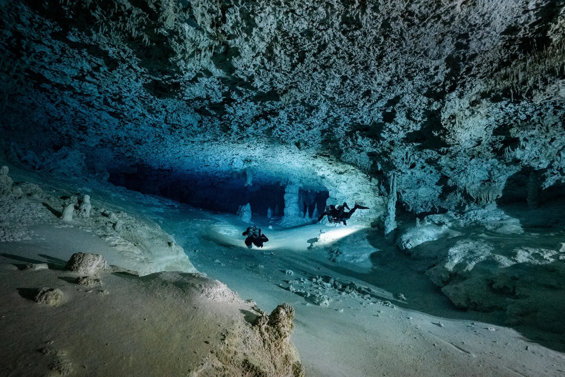 Twee duikers in een overstroomde grot in Mexico, tussen stalactieten en stalagmieten
