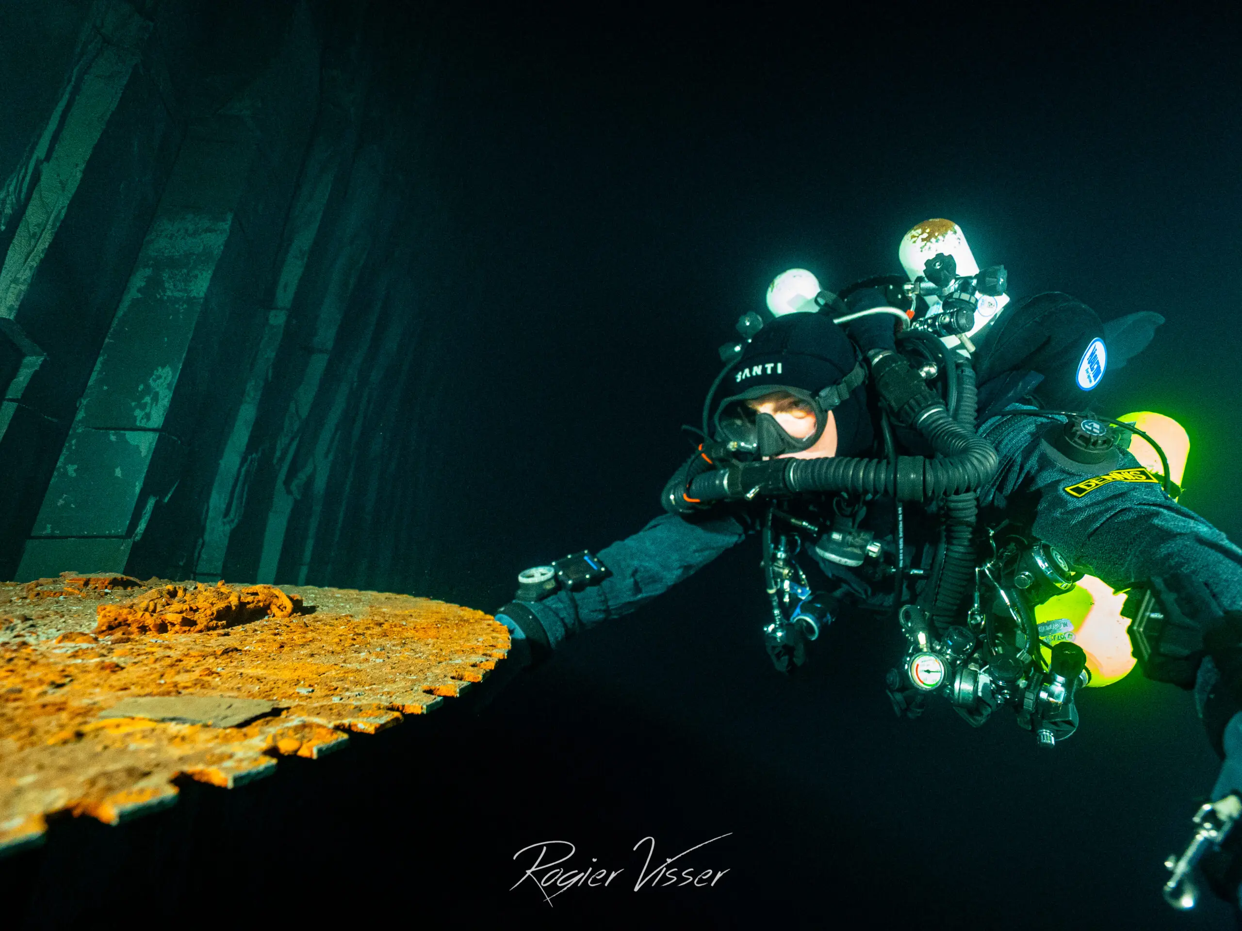 Duiker met rebreather naast een verroeste plaat diep in een ondergelopen mijn